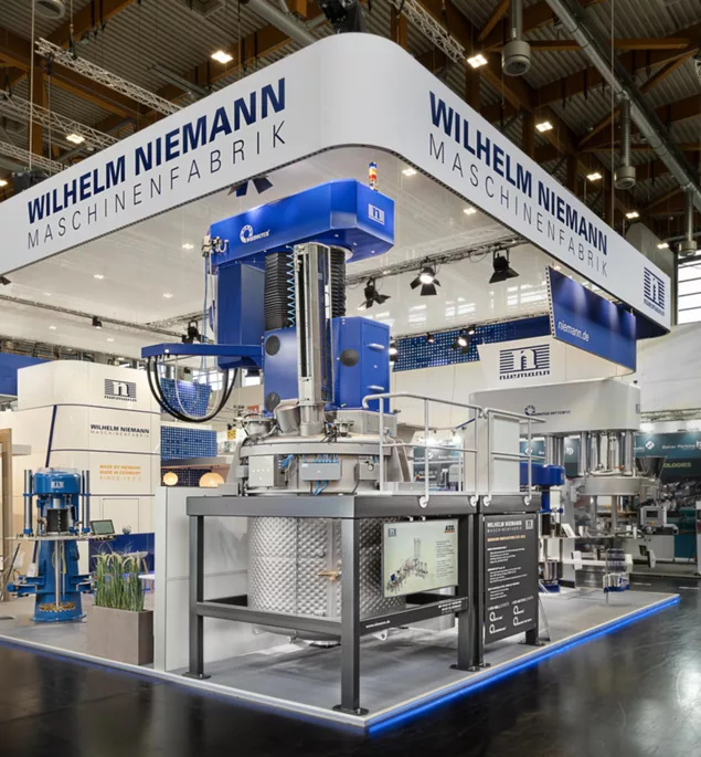 Gesamtansicht des Niemann-Stands mit vollständig aufgebauter Maschineninstallation und Besucherandrang.