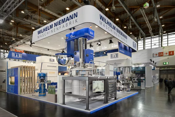 [Translate to English:] Gesamtansicht des Niemann-Stands mit vollständig aufgebauter Maschineninstallation und Besucherandrang.