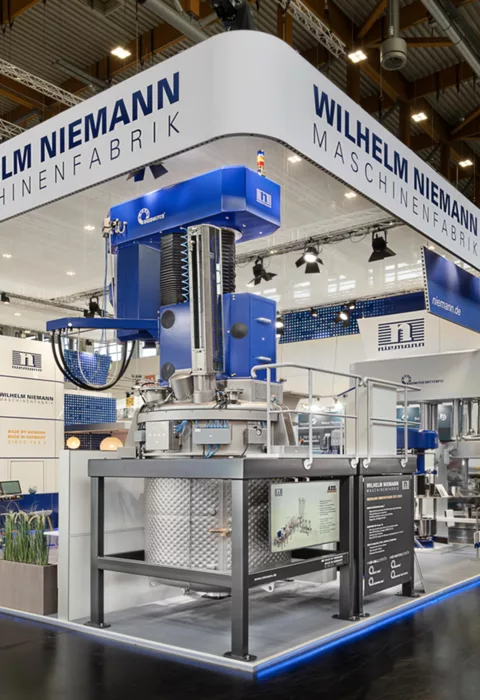 [Translate to English:] Gesamtansicht des Niemann-Stands mit vollständig aufgebauter Maschineninstallation und Besucherandrang.