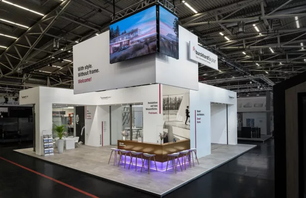 Moderner Messestand mit integriertem Bildschirm und stylischem Barbereich.