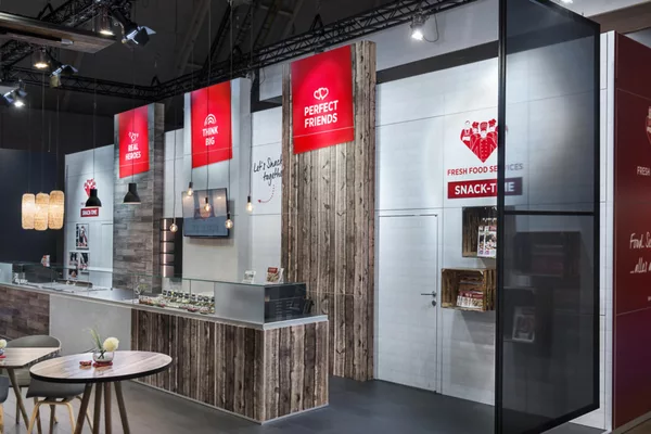 Seitenansicht des Standes mit Theke, Holzverkleidung und Pendelleuchten.