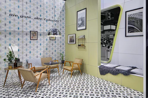 Retro-Ecke mit Sitzecke, Mustertapete und dekorativen Details auf dem Act’o-soft Messestand
