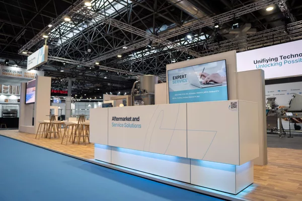 Weiße Infotheke mit blauer LED-Kante und Monitor „EXPERT SERVICE“, Barhocker, Gang mit blauem Teppich.