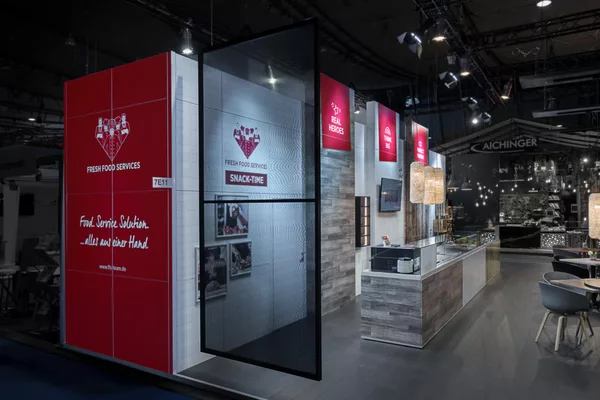 Perspektive mit Fokus auf das transparente Mesh-Logo und die Gastronomie-Möblierung.