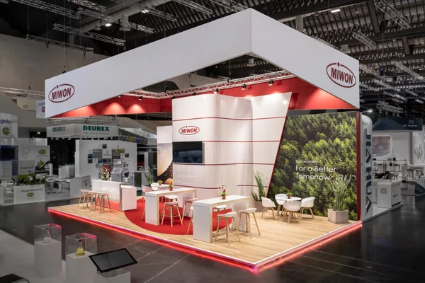  Messestand mit Hochglanzfläche, Holzboden und Theke auf rotem Teppich