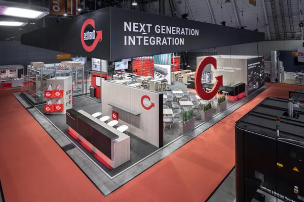 [Translate to English:] Gebhardt Messestand auf der LogiMAT 2024 mit schwebendem XXL-Logo und modernem Lounge-Bereich