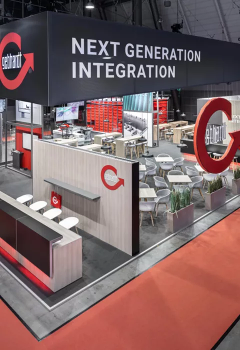 [Translate to English:] Gebhardt Messestand auf der LogiMAT 2024 mit schwebendem XXL-Logo und modernem Lounge-Bereich