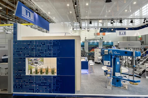 [Translate to English:] Seitenansicht des Standes mit gepunktetem Wanddesign, Pflanzenmodul und Blick auf die Maschinenhalle.