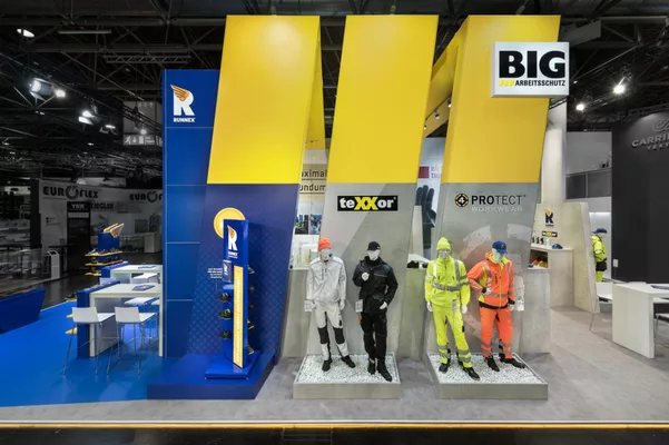  Frontalansicht des Standes mit gelben Elementen und Slogan.