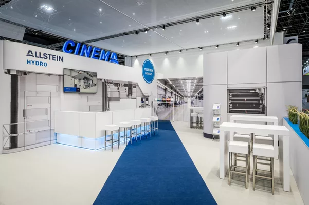 Blick auf den Standbereich „CINEMA“ mit LED-Schriftzug, Barhockern und imposanter Maschinenvisualisierung.