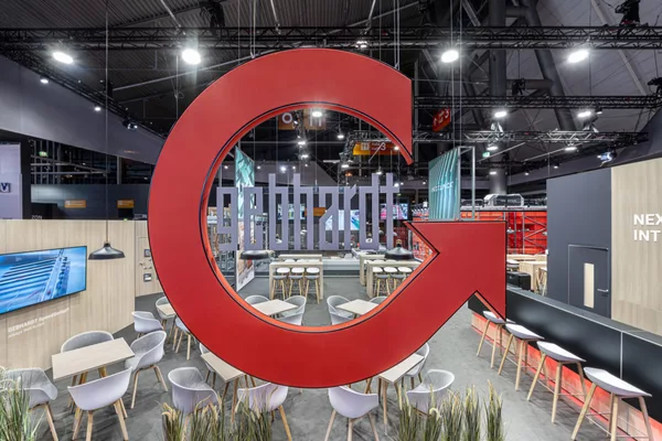 [Translate to English:] Zentraler Blick durch das schwebende Gebhardt-Logo – moderner Messestand in Schwarz und Holzoptik